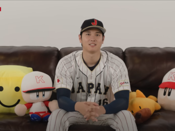 Shohei Ohtani during a promotional interview for Konami's baseball video games. He's on a couch alongside plushies for Pawapuro and Prospi characters.